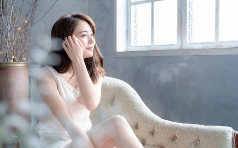 ソファーに座って窓辺でほほ笑む女性